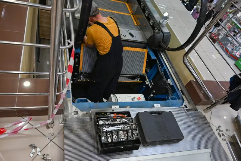 man repairs escalator steps inside standing with 2025 03 08 17 11 23 utc