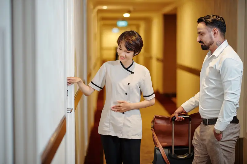 young pretty hotel manager uniform explaining guest how open room door with electronic key 5